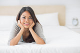 Young pretty girl lying on her bed smiling at camera