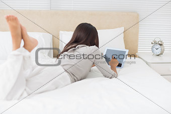 Young girl lying on bed using her tablet