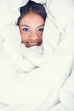Pretty girl wrapped up in her duvet smiling at camera