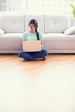 Pretty girl sitting on a floor using laptop