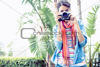 Brunette taking a photo outside smiling at camera