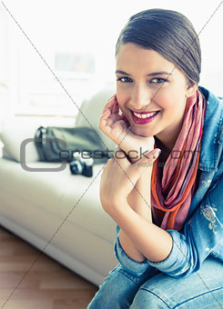 Young brunette sitting on sofa looking at camera