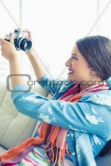 Smiling brunette sitting on sofa taking a selfie