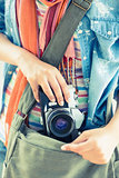 Young woman taking camera from her bag