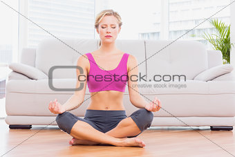 Slim blonde meditating in lotus pose