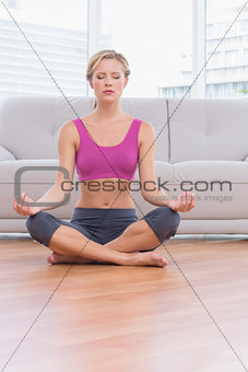 Fit blonde meditating in lotus pose