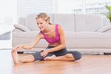 Fit blonde sitting on floor stretching her leg