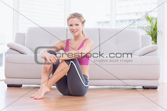 Fit blonde sitting on floor smiling at camera