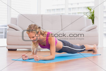 Fit blonde in plank position on exercise mat