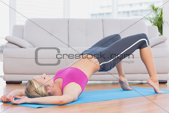 Slim blonde lifting her pelvis on exercise mat