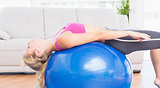 Slim blonde stretching her back on exercise ball