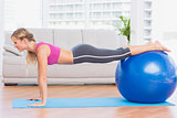 Slim blonde in plank position using exercise ball