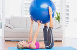 Cheerful fit blonde holding exercise ball between legs