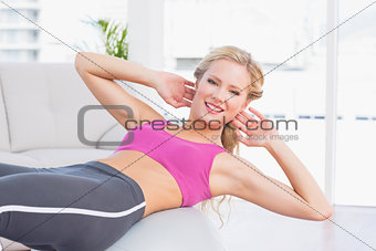 Happy fit blonde doing sit ups with exercise ball