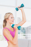 Toned blonde lifting dumbbells and smiling