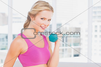 Pretty blonde lifting dumbbells and smiling at camera