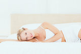 Pretty blonde lying on her bed smiling at camera