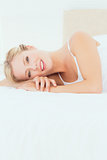 Pretty young blonde lying on her bed smiling at camera