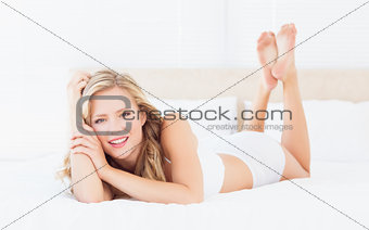 Pretty young blonde lying on her bed looking at camera