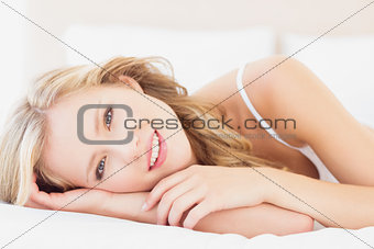 Natural young blonde lying on her bed looking at camera