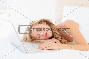 Cute young blonde sleeping beside her laptop