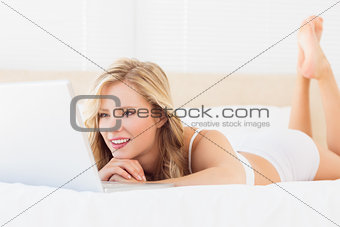 Smiling young blonde watching her laptop