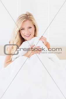 Sexy young blonde covering herself with duvet