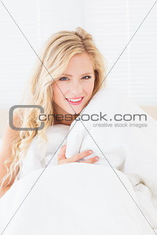 Sexy young woman covering herself with duvet