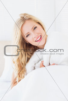 Pretty young woman covering herself with duvet
