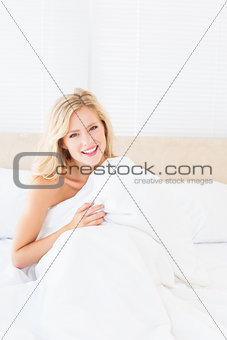 Attractive young blonde covering herself with duvet