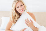 Attractive young blonde covering herself with pillow