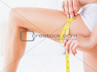 Slim woman measuring her thigh