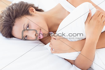 Smiling pretty brunette lying on bed hugging pillow