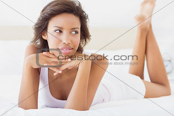 Smiling brunette lying on bed thinking