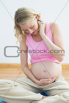 Glowing pregnant blonde smiling at bump