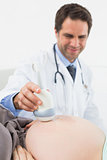 Happy doctor doing a sonogram scan on pregnant woman