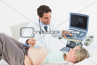 Cheerful doctor doing a sonogram scan on pregnant woman