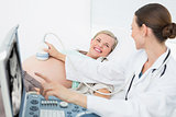 Happy female doctor showing woman her baby on ultrasound