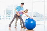 Trainer exercising with blonde pregnant client and exercise ball