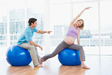 Trainer exercising with blonde pregnant client on exercise balls