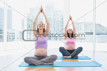 Happy pregnant women in yoga class sitting in lotus pose