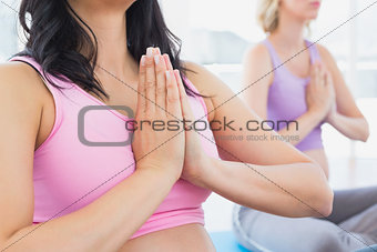 Meditating pregnant women at yoga class in lotus pose
