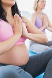 Meditating pregnant women at yoga class with hands together