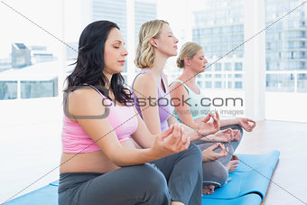 Relaxed pregnant women meditating in yoga class