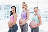 Happy pregnant women standing in a row