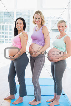 Smiling pregnant women standing in a row