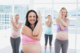 Happy pregnant women in yoga class standing in eagle pose