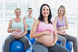 Smiling pregnant women sitting on exercise balls