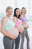 Happy pregnant women standing in a line holding their bumps