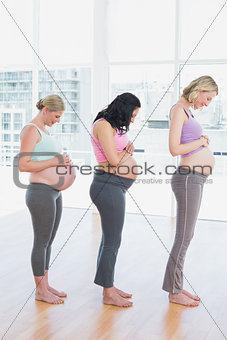 Happy pregnant women standing in a line smiling at bumps